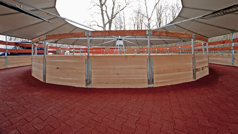 Na fotografii je moderný, zastrešený kruhový vodič pre kone. Pochôdzna plocha je kompletne vydláždená červenou gumovou dlažbou – protišmykovou, priepustnou a šetrnou ku kĺbom. Elastický povrch zabezpečuje bezpečný pohyb koní za každého počasia a pri každom chode. Dlažba je stabilná, trvácna a nenáročná na údržbu. Ideálna voľba pre jazdecké areály, chovné stanice alebo konské kliniky, ktoré vyžadujú spoľahlivý, zvieratám prispôsobený a odolný povrch.